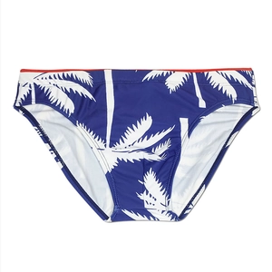 Close-up of men's navy blue swim briefs with white palm tree print and red waist trim