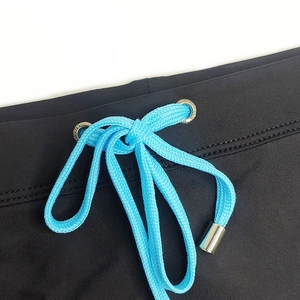 Detail of mens black swim trunks showing blue drawstring and silver metal eyelets