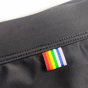 Close-up of black swim trunks showing elastic fabric and rainbow stripe tag detail