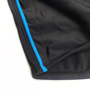 Detail of black swim trunks showing elastic fabric with blue piping and reinforced stitching