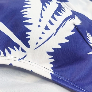Detail of tropical palm leaf print on blue men's swim trunks with durable stitching