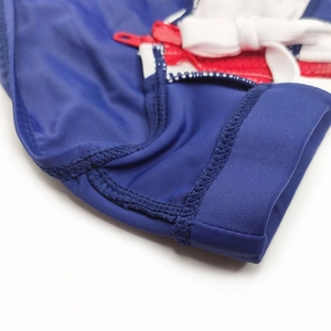 Détail du slip de bain bleu marine avec zip rouge, nœud blanc et coutures de précision