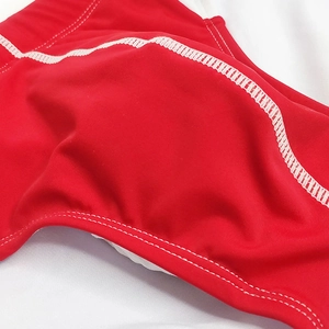 Close-up of red swim trunks featuring durable white contrast stitching and elastic fabric