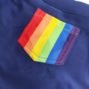 Detail of navy blue swim trunks featuring a rainbow striped pocket and durable stitching