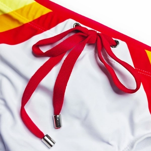 Detail of men's rainbow swim briefs featuring red drawstring and silver eyelets on the waist