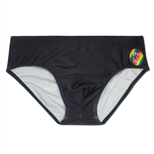 Close-up of black men's swim trunks featuring a Love is Love rainbow badge detail