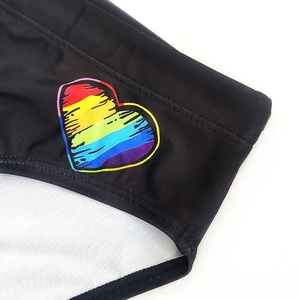 Nahaufnahme von schwarzem Ripp-Badestoff mit buntem Regenbogen-Herzprint und feinen Nähten