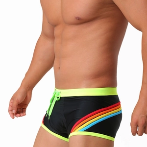 Close-up of black swim trunks with neon green trim and rainbow side stripe detail