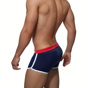 Detail of navy blue mens swim trunks with red waistband and white side piping trim