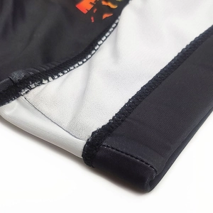 Detail of high-elasticity men's swimwear fabric with flatlock stitching and orange print