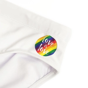 Detail of quick-dry swim briefs with rainbow Love is Love patch on white fabric