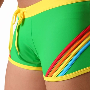 Detail of green men's swim trunks with vibrant rainbow stripes and yellow drawstrings