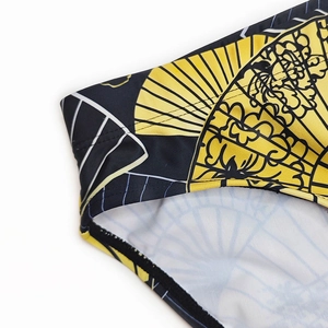 Detailed close-up of quick-dry swim briefs featuring a vibrant yellow fan print pattern