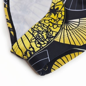 Macro detail of men's swim briefs showing retro abstract print and reinforced stitching