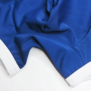 Close-up of royal blue swim trunks showing white piping and elastic knit fabric texture