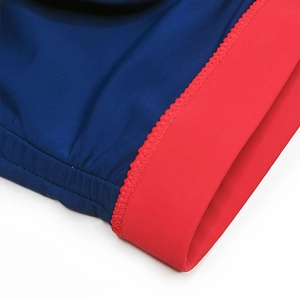 Close-up of precise stitching and red ribbed elastic edge on navy swim trunks