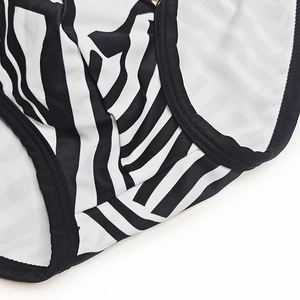 Detailed close-up of men's swim briefs featuring black and white irregular stripe patterns