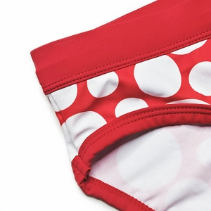 Détail macro du maillot de bain à pois rouges montrant les coutures renforcées à double aiguille