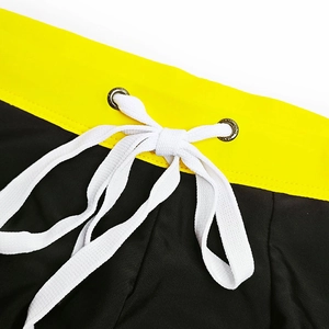 Detail of men's swim trunks with yellow waistband, adjustable white drawstring and metal eyelets