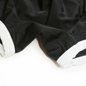 Detail of color-block swim trunks featuring black fabric and white elastic piping edges