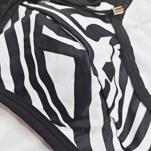 Detail of swimsuit fabric with black and white abstract print and gold metal drawstring tip