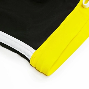 Close-up of contrast color swimming trunks with yellow piping and elastic drawstring details