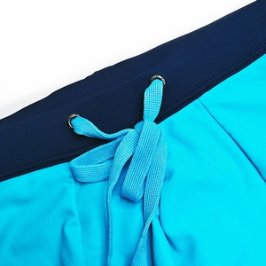 Detail of men's swim trunks featuring color-block design and drawstring with metal eyelets
