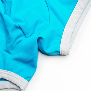 Close-up of sky blue men's swim trunks featuring premium white piping and elastic stitching