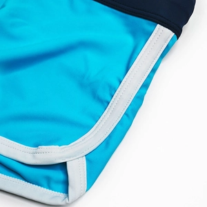 Detailed close-up of blue color-block swim trunks with white side stripes and fine stitching
