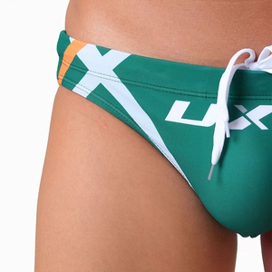 Gros plan du slip de bain vert foncé avec bandes orange et détails du cordon de serrage