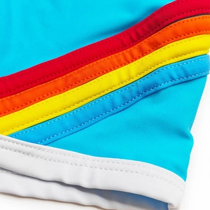 Close-up detail of blue fitness swim shorts with colorful rainbow stripes and white piping