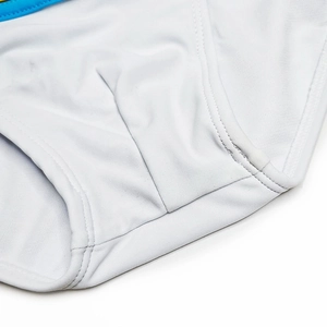 Gros plan détaillé du slip de bain blanc montrant les coutures et le tissu souple