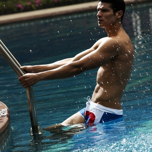 Action shot of men's tricolor patchwork swim trunks with white drawstring by the pool