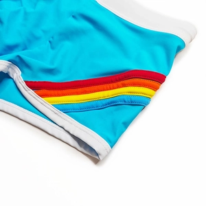 Detail of blue athletic swim trunks featuring rainbow side stripes and white piping