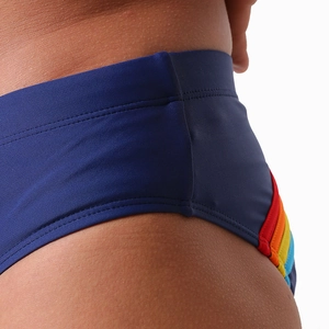 Gros plan détaillé des rayures arc-en-ciel sur le slip de bain bleu foncé pour homme en stretch