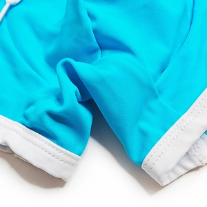 Detail view of sky blue swimwear fabric with white edge binding and neat stitching