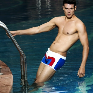Close-up of men's tricolor patchwork swim trunks with white drawstring by the pool