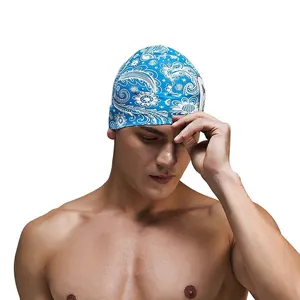 Detail of blue silicone swim cap with white paisley pattern worn by male model