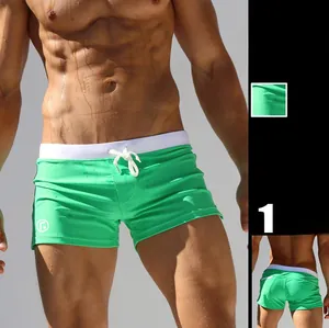 Detail view of bright green men's low-waist swimming trunks with white drawstring and logo