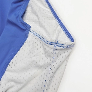 Détail du tissu extensible bleu et des coutures en maille losange sur le body homme