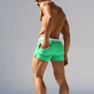 Close-up of grass green low-waist swimming trunks with white belt and rear zipper pocket