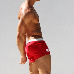 Detail of red quick-dry men's swim trunks with side slits and white contrast waistband