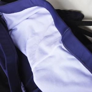 Detail of men's dark purple swim trunks showing white mesh lining and black drawstring waist