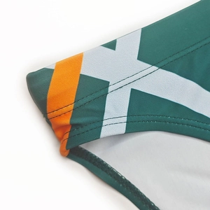 Détail d'un slip de bain homme avec coutures doubles et rayures latérales vert et orange