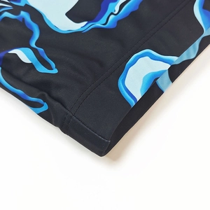 Close-up of double-stitched seam on high-elasticity swimming trunks with blue print