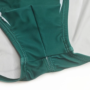 Gros plan du slip de bain vert foncé montrant les doubles coutures et le tissu élastique