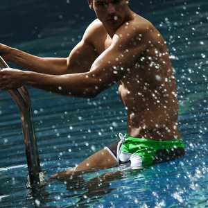 Close-up of green, black and white patchwork men's swim trunks with drawstring detail