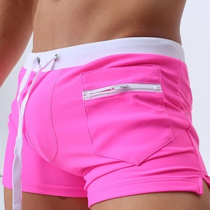 Detail of neon pink swim trunks featuring a white drawstring waist and functional side zipper pocket