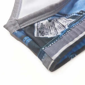 Detailed close-up of men's swim trunks with denim texture print and dollar bill patterns