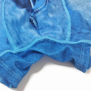 Macro shot of reinforced seams and denim print texture on men's stretch swim trunks
